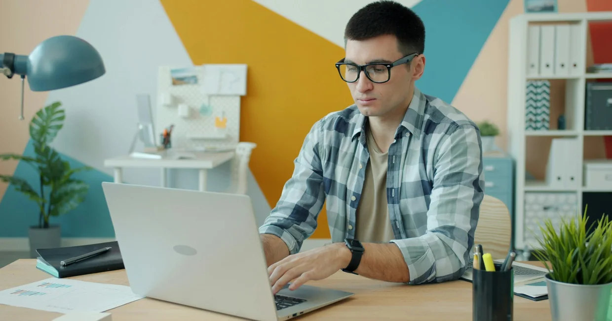 An attorney working alone at a laptop in a small bright office, files and stationery on the desk beside them