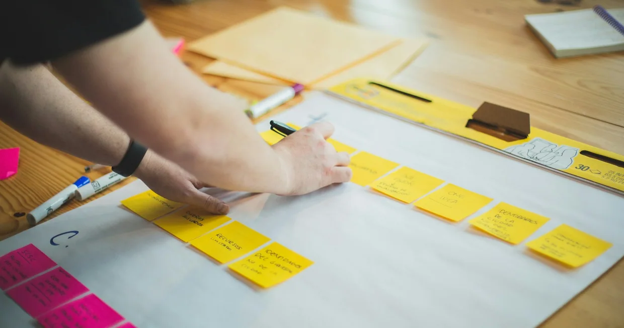 A person writing notes on a sheet of white paper at a desk