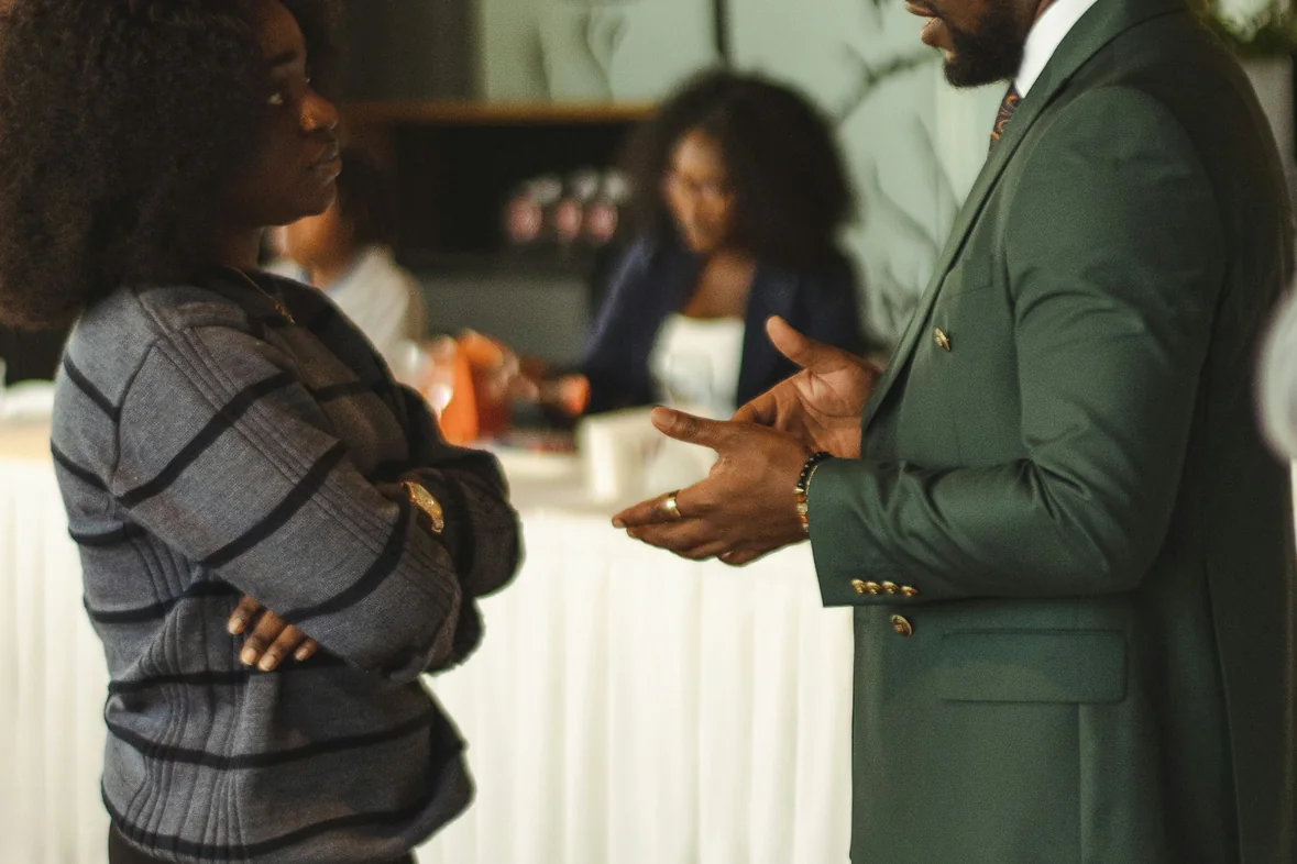 Two people talking at a networking event, one gesturing while the other listens