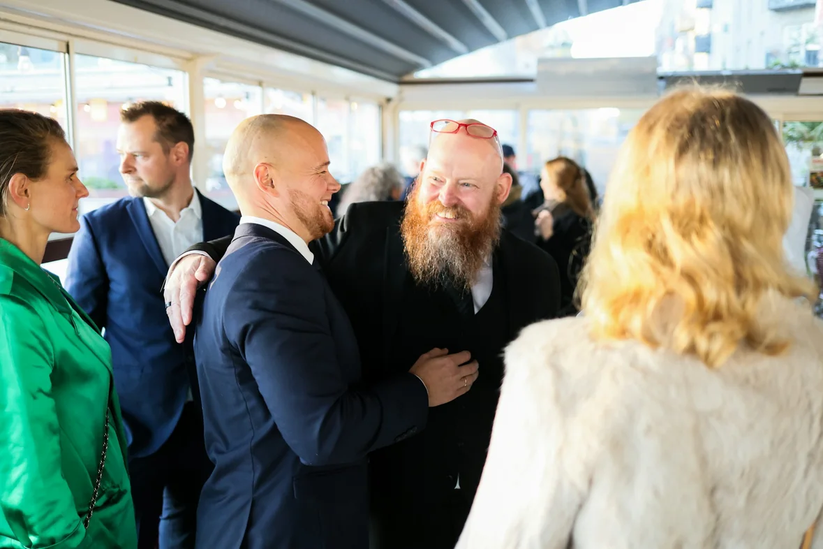 Two people greeting each other warmly at a busy professional reception