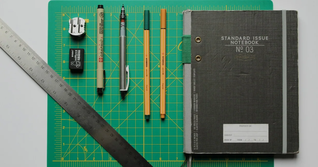 A black spiral notebook lying open with pencils resting beside it