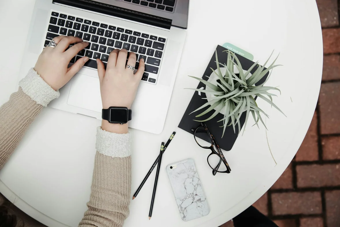 Someone using a laptop beside an aloe vera plant on a bright desk