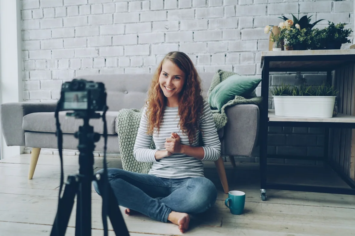 Someone sitting on the floor filming themselves with a camera