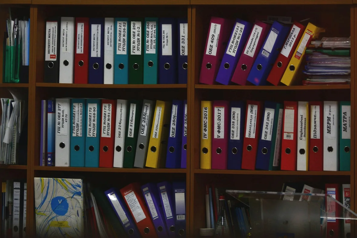 Wooden shelves filled with rows of labelled ring binders and folders