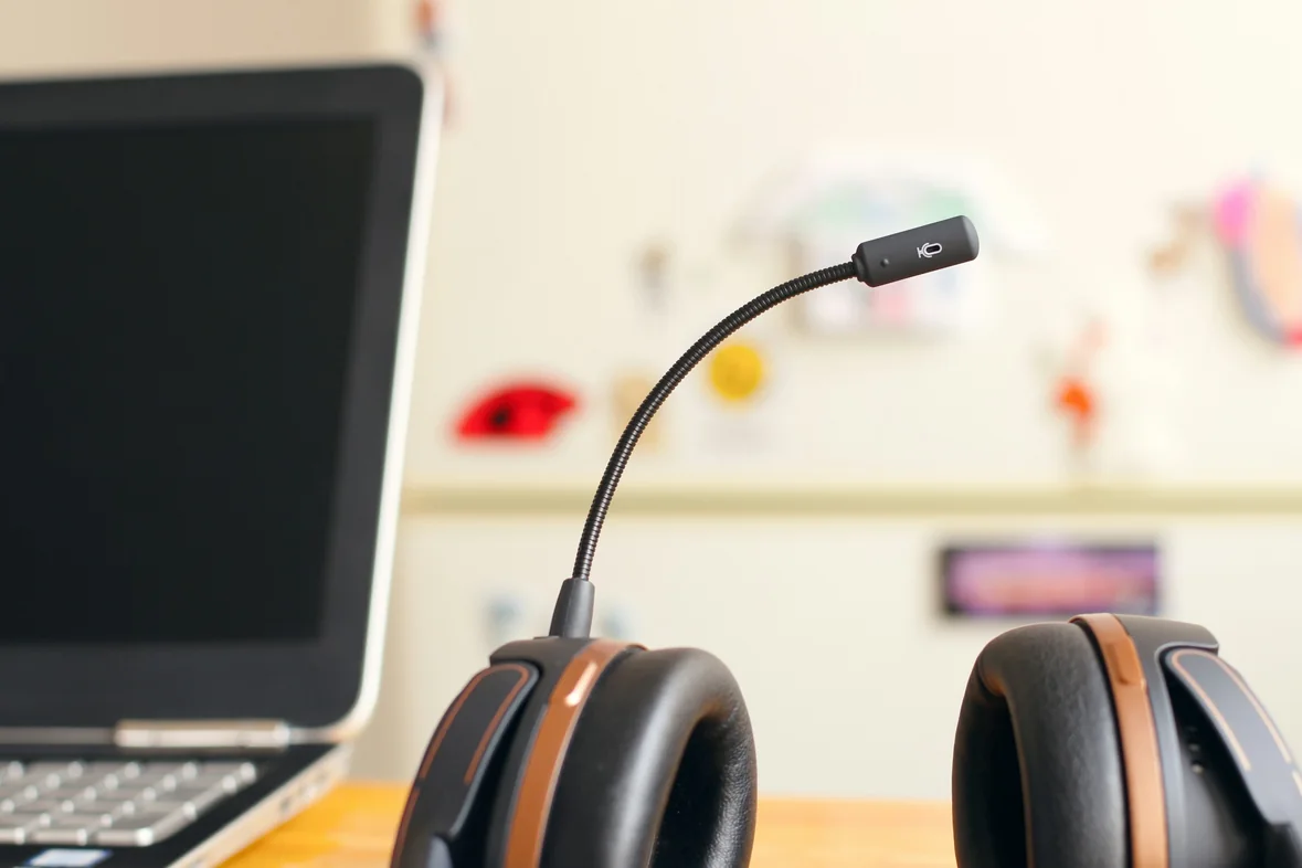 A headset resting on a desk beside an open laptop