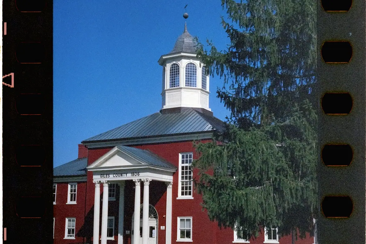 A red brick public building with white columns and a cupola
