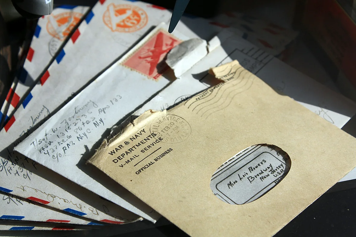 A pile of old opened envelopes and posted letters stacked on a dark surface