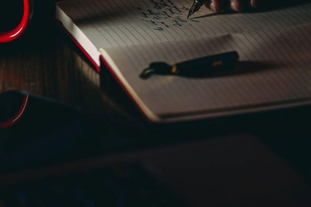 Someone writing notes by hand on a sheet of white paper