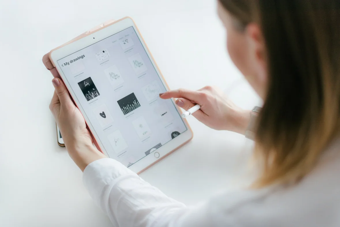Someone holding a tablet and tapping the screen, seen over their shoulder