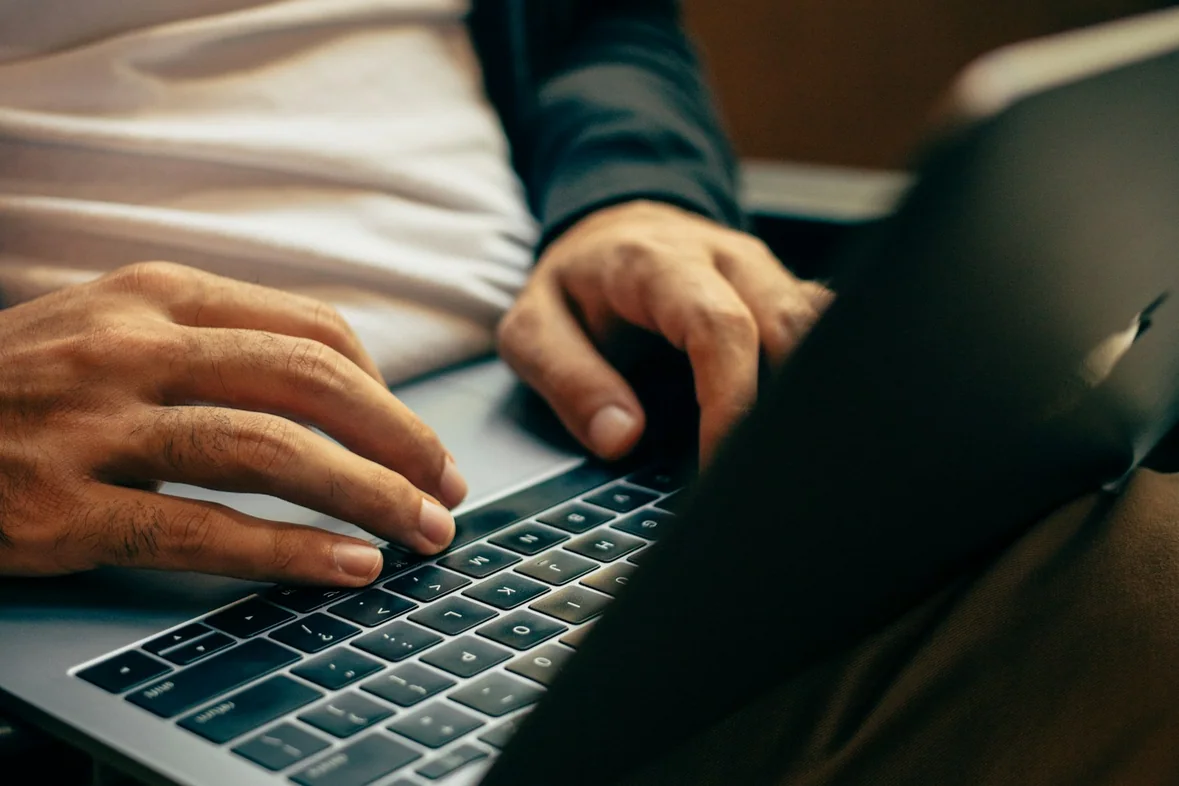 A person using a laptop at a desk with natural light