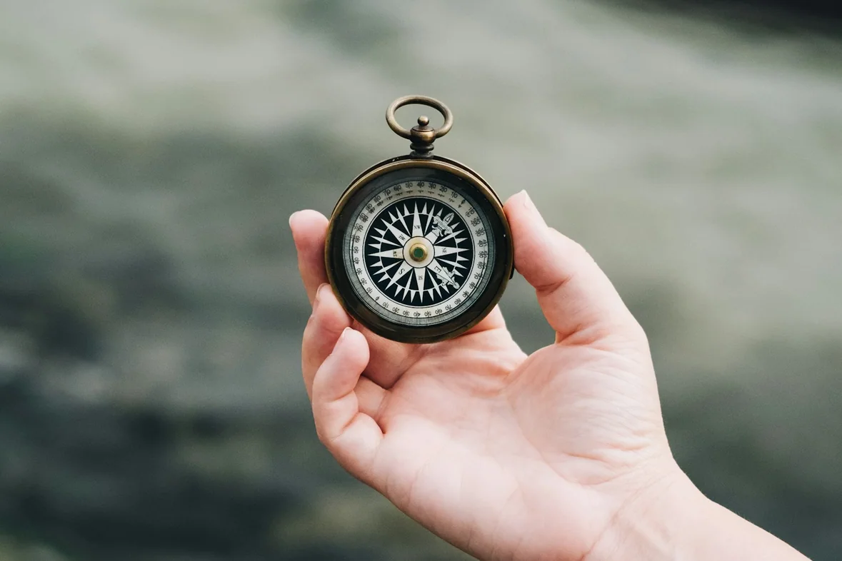 A hand holding a black and white compass