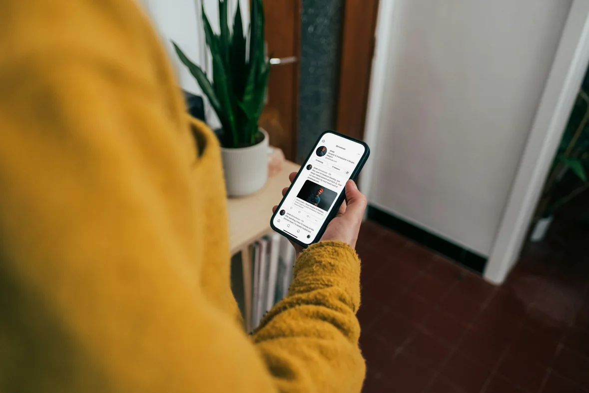 A close view over someone's shoulder of a phone held in one hand, a page of content open on the screen