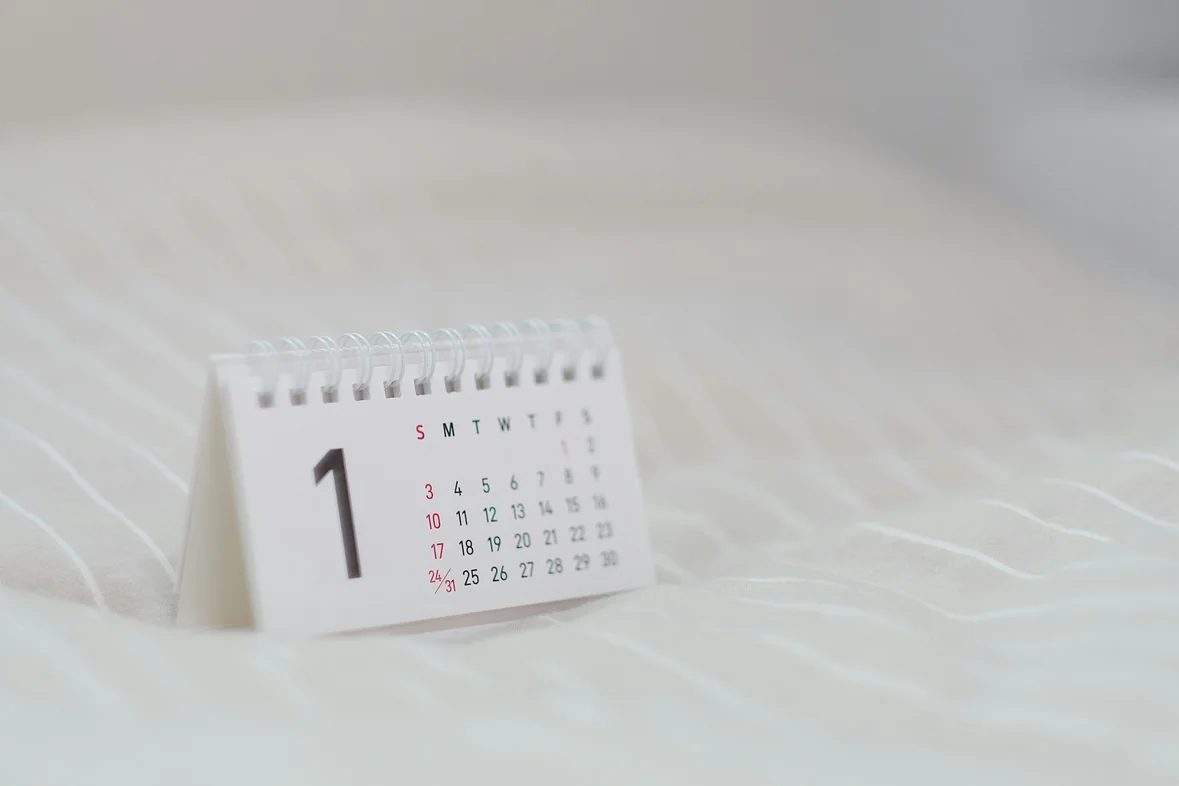 A blank white monthly calendar laid out on a pale surface