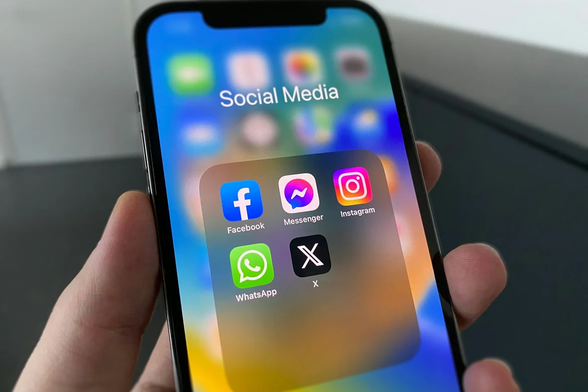 A close view of someone holding a phone showing rows of social media app icons