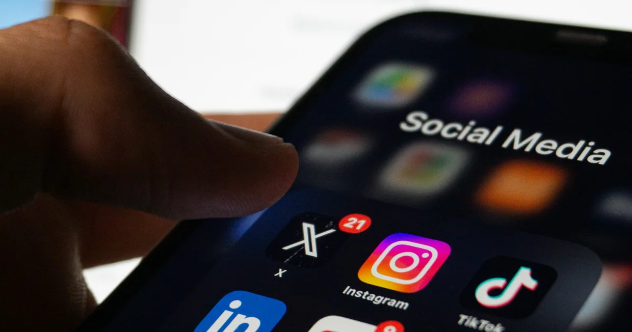 A hand holding a smartphone with social media applications open on the screen