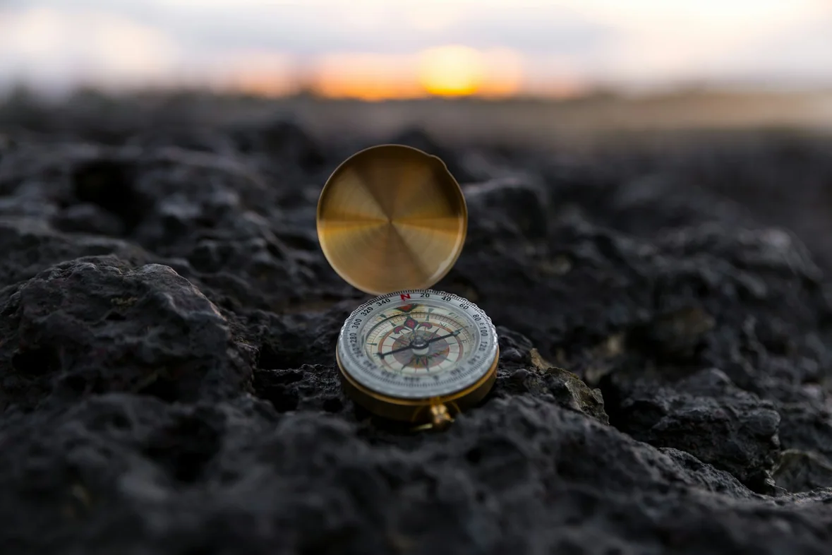 A round gold-coloured compass on a pale surface