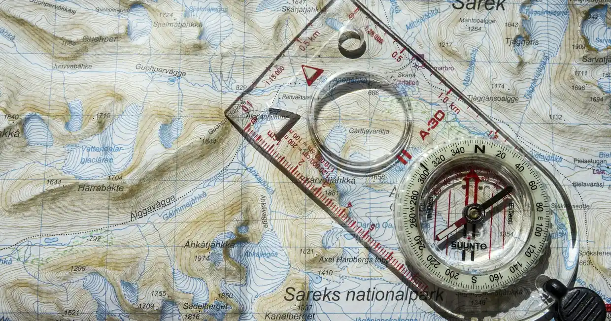 A compass and ruler resting on a printed topographic map