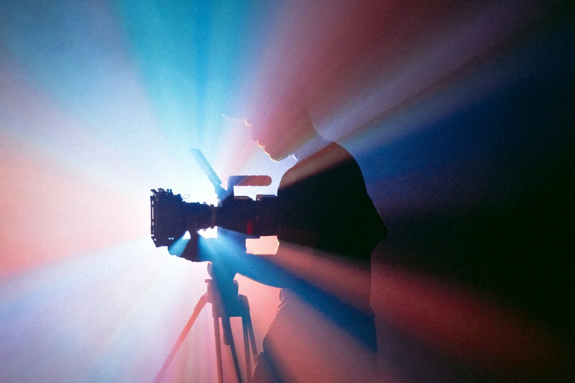 Someone filming with a camera mounted on a tripod indoors