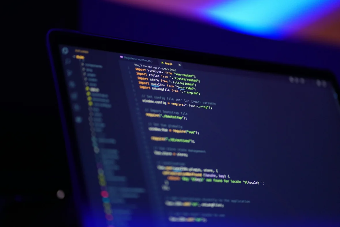 A laptop screen filled with colourful syntax-highlighted code in a darkened room