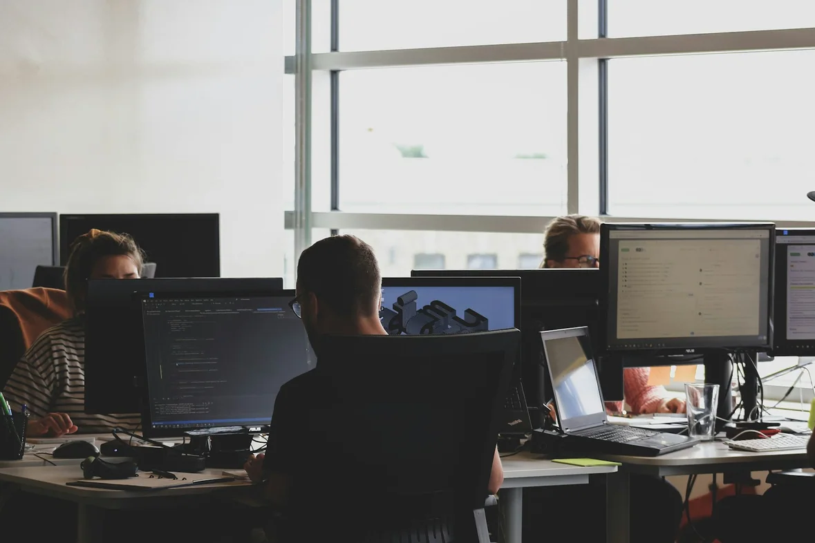 Colleagues seated in front of computer monitors reviewing work together