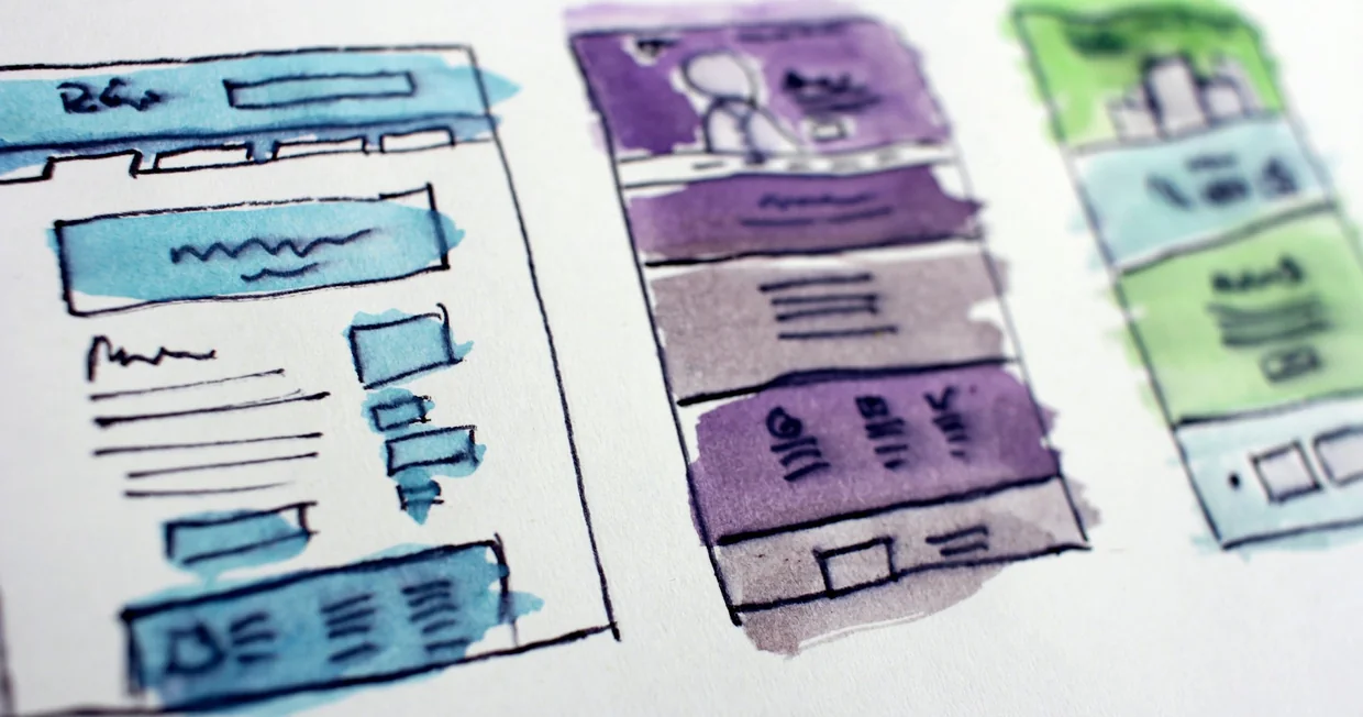 Hand-drawn watercolour wireframe sketches of website page layouts on white paper