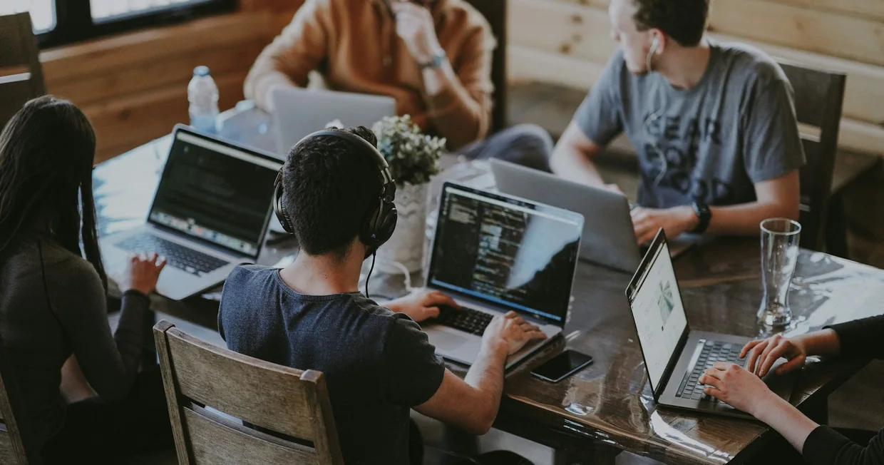 A group of people gathered around a laptop in a bright workspace