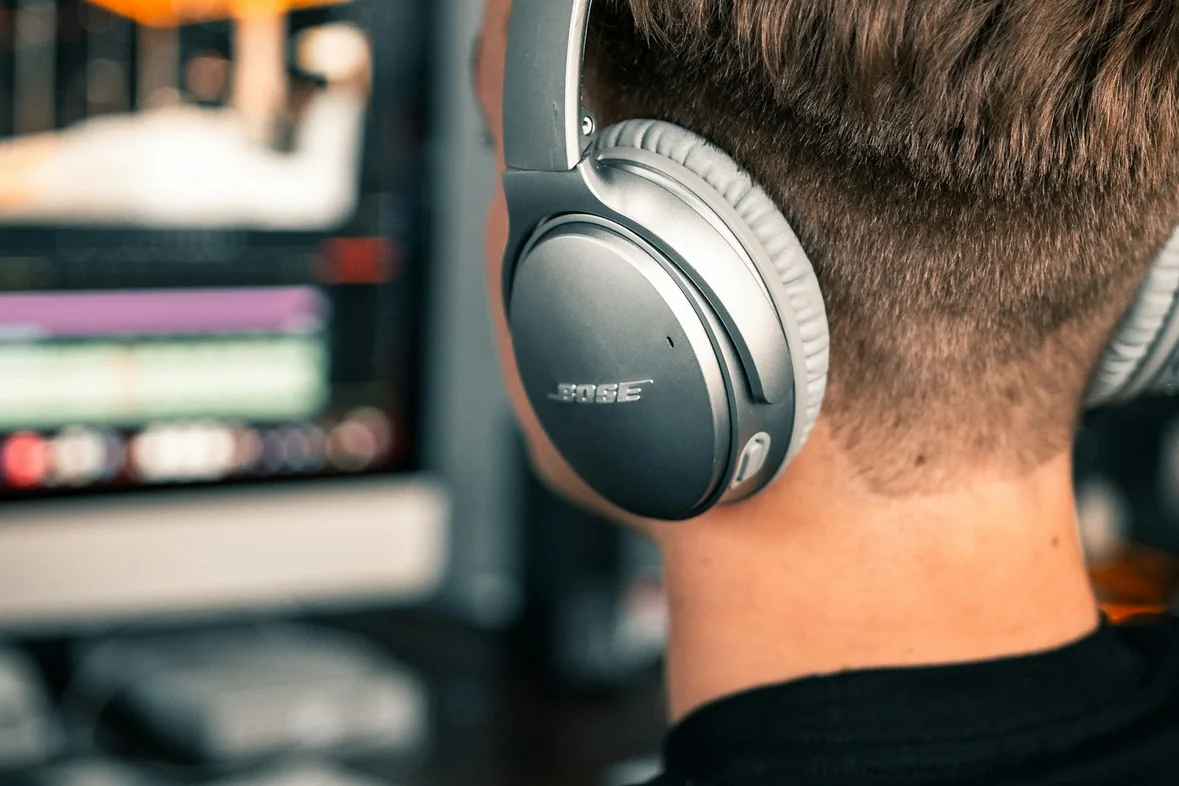 Someone wearing over-ear headphones concentrating at a desk