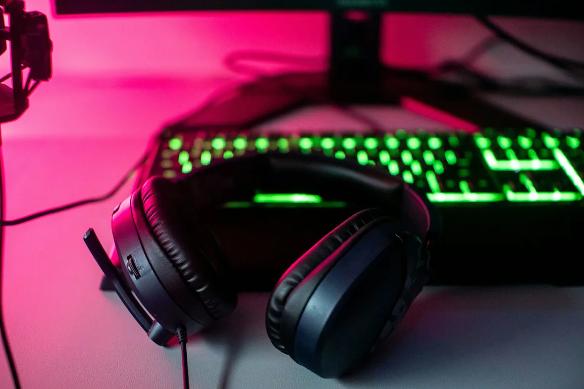 A headset resting beside a computer keyboard on a desk