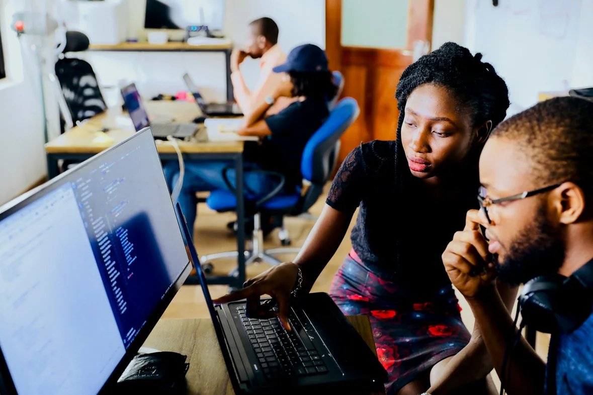 A woman and a man working together in front of a monitor