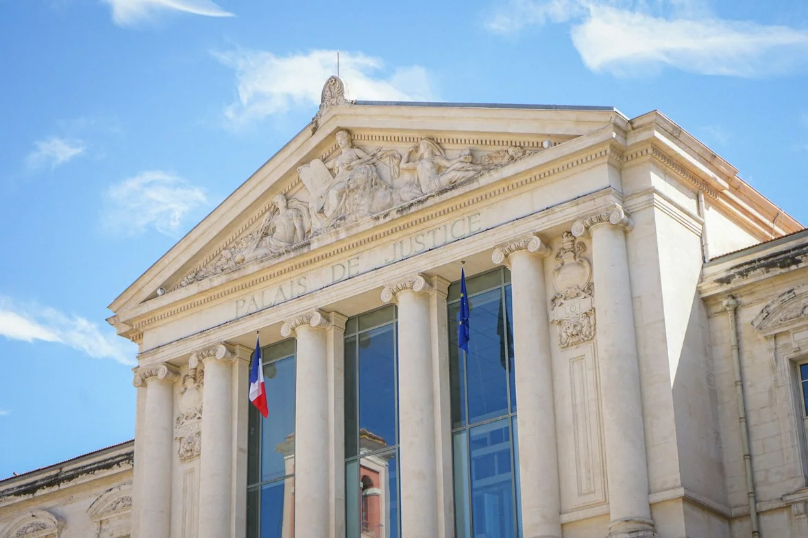 A grand neoclassical building with flags along its facade