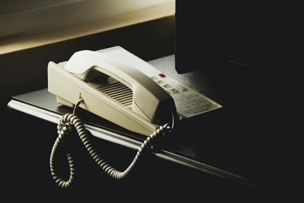 A desk telephone handset resting in its cradle beside a monitor