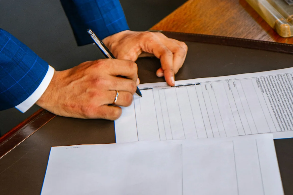 A hand completing a printed form on a desk