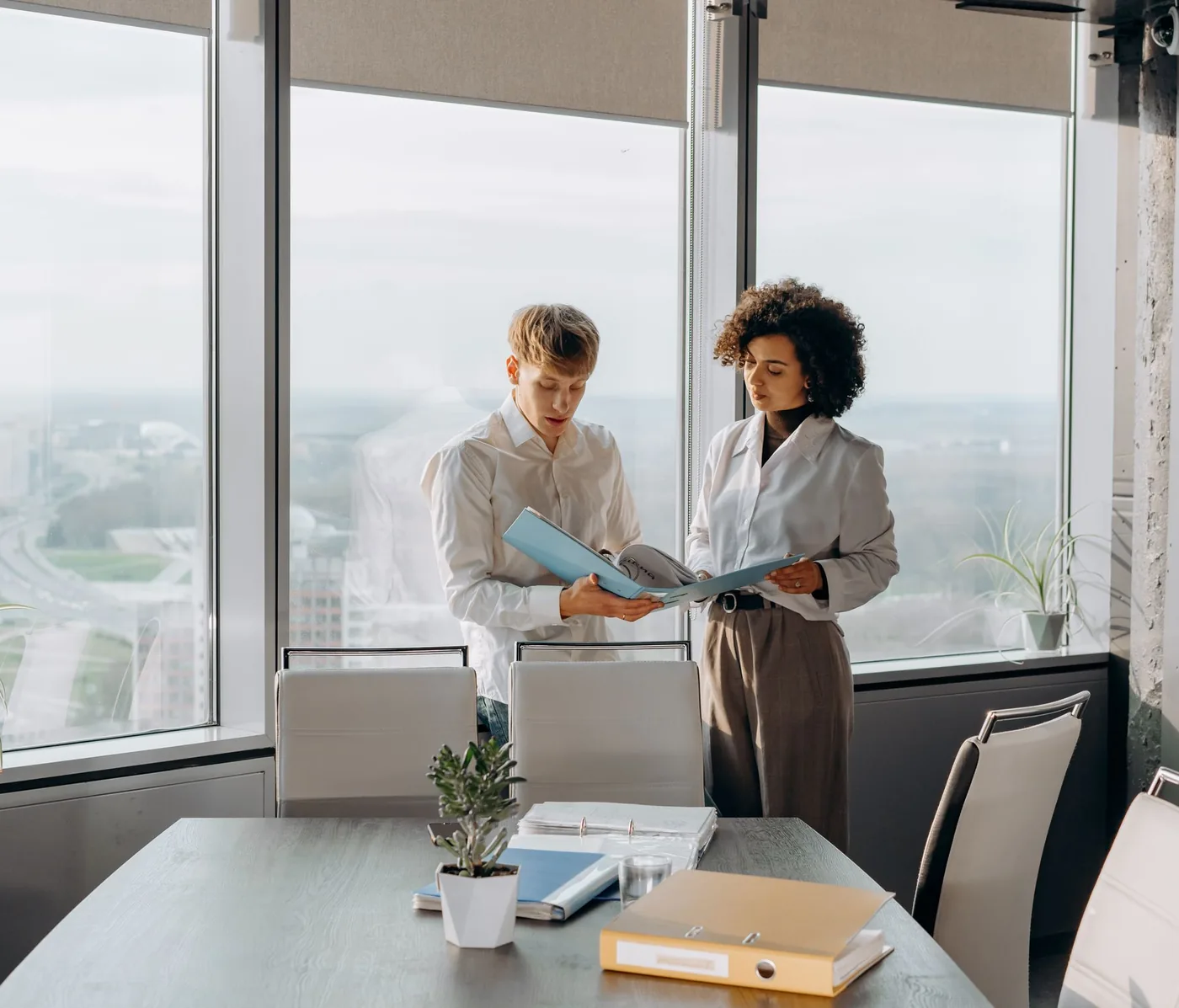 Two colleagues reviewing a client file together beside a window