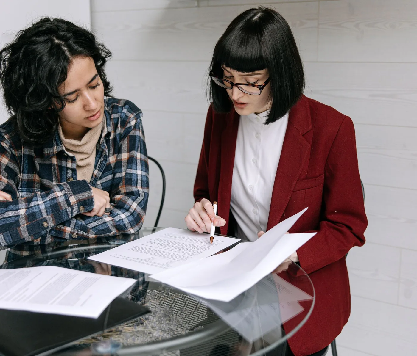 Two colleagues reviewing a report together at a glass table